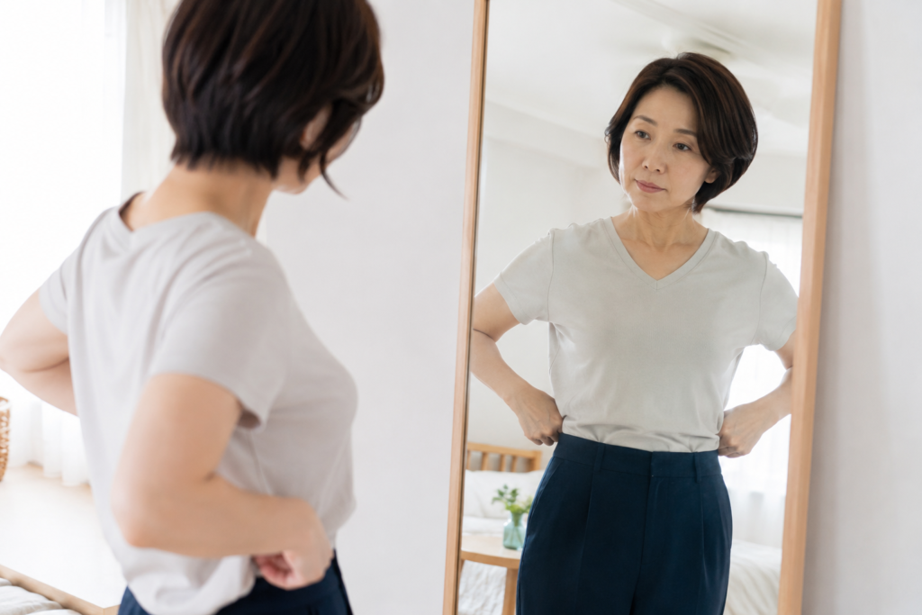 鏡の前でウエストを気にする女性